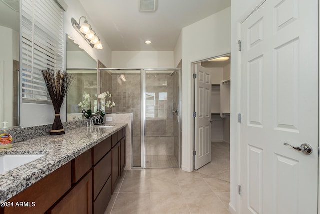 bathroom with a shower with door, vanity, and tile patterned flooring