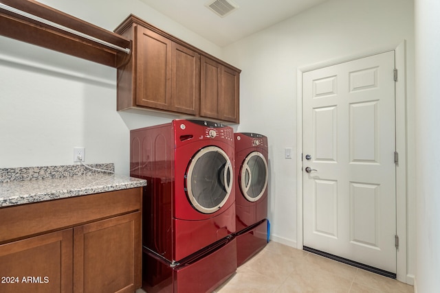 laundry area with light tile patterned flooring, washer and dryer, and cabinets