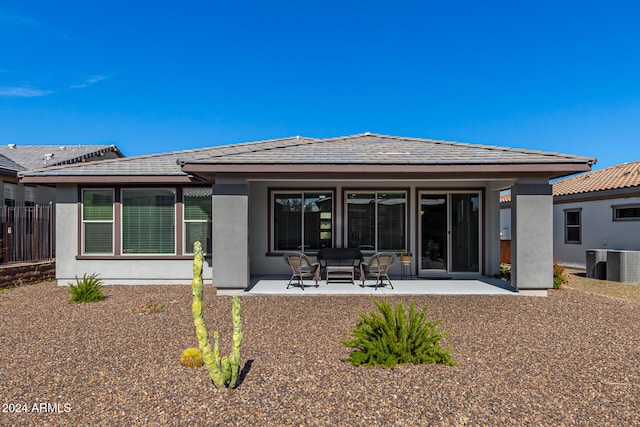 rear view of property with cooling unit and a patio