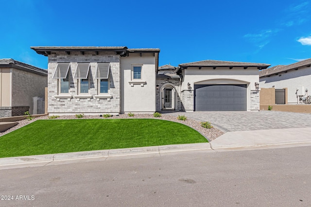 view of front of home featuring stucco siding, an attached garage, decorative driveway, and a front yard