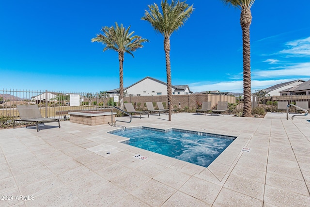 view of pool with fence, a hot tub, and a patio area