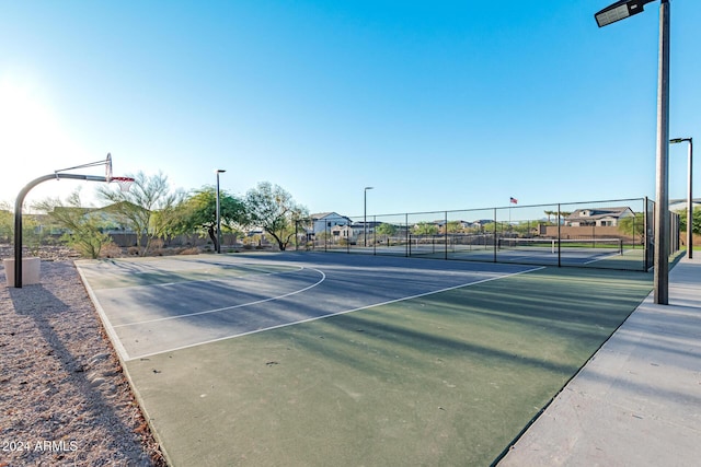 view of basketball court with a tennis court, community basketball court, and fence