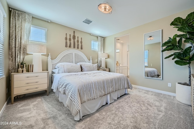 bedroom featuring connected bathroom and light carpet