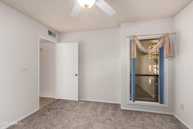 carpeted spare room with ceiling fan and a textured ceiling