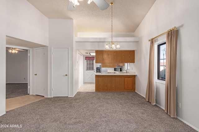 kitchen with kitchen peninsula, light colored carpet, hanging light fixtures, and ceiling fan with notable chandelier