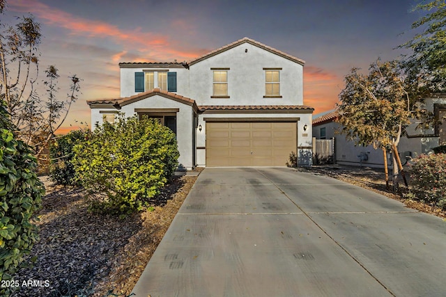 mediterranean / spanish home featuring driveway, stucco siding, an attached garage, and a tiled roof