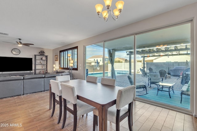 dining area featuring ceiling fan with notable chandelier, visible vents, and wood finish floors