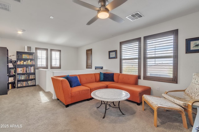 living area featuring a ceiling fan, visible vents, and light colored carpet