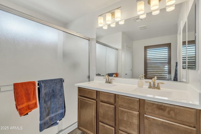 bathroom featuring double vanity, a stall shower, visible vents, and a sink