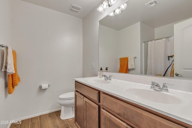 bathroom with toilet, visible vents, a sink, and wood finished floors