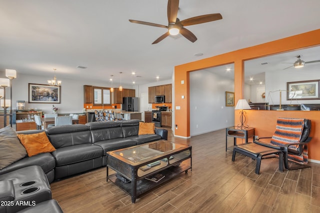 living area with dark wood-style floors, recessed lighting, baseboards, and ceiling fan with notable chandelier