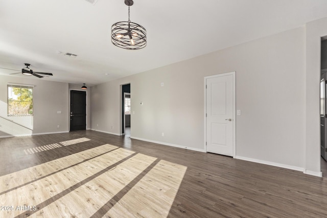 unfurnished living room with ceiling fan with notable chandelier and dark hardwood / wood-style floors