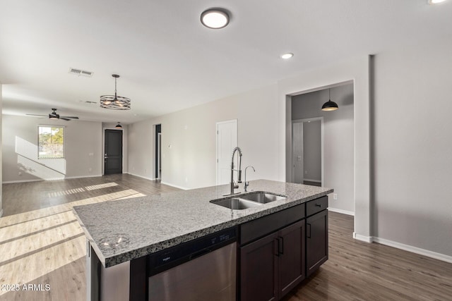 kitchen with sink, pendant lighting, dishwasher, light stone countertops, and a kitchen island with sink