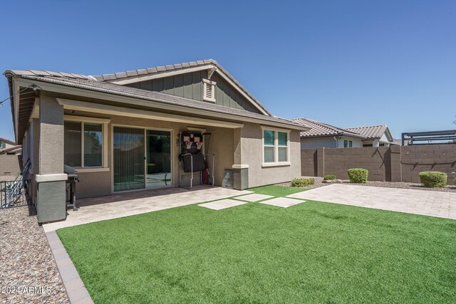 back of property with a lawn and a patio area