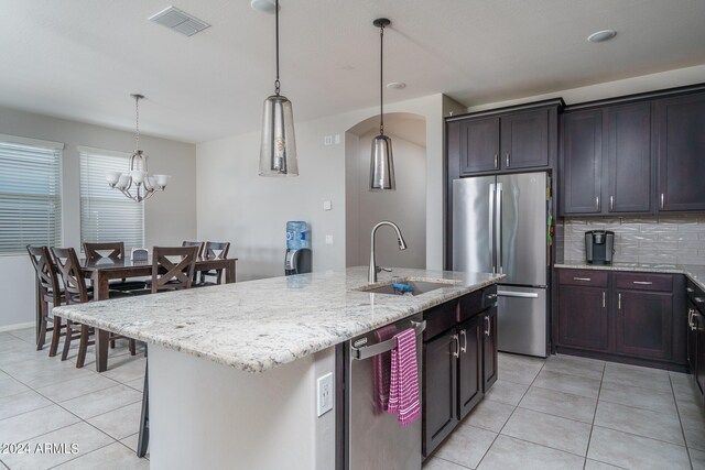 kitchen featuring pendant lighting, sink, a center island with sink, stainless steel appliances, and a notable chandelier