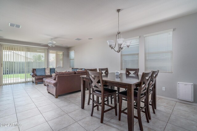 tiled dining area with ceiling fan with notable chandelier