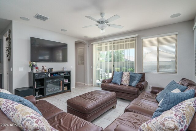 tiled living room featuring ceiling fan and a fireplace