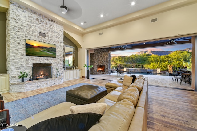 living room with ceiling fan, a fireplace, and hardwood / wood-style floors