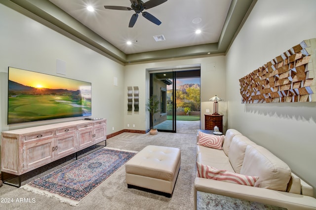 living room featuring light carpet, a raised ceiling, and ceiling fan