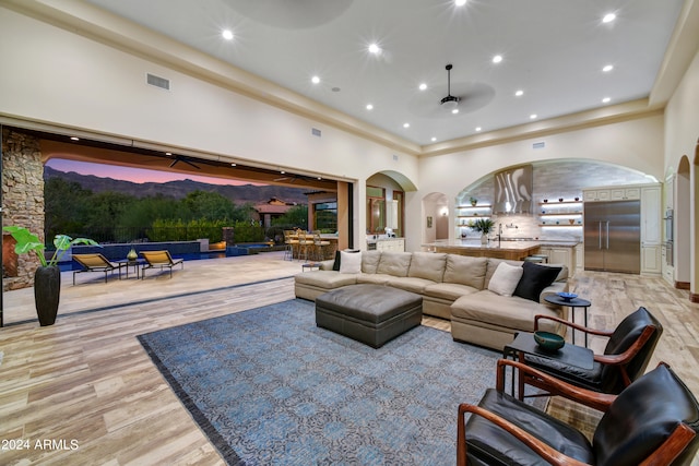 living room with light wood-type flooring and a towering ceiling