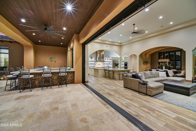 interior space featuring bar area, wooden ceiling, a high ceiling, and ceiling fan