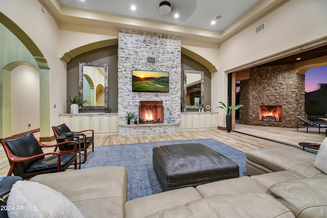 living room with light wood-type flooring, a fireplace, and a towering ceiling