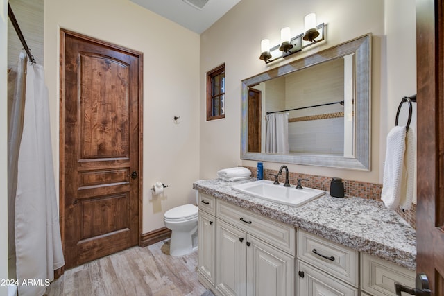 bathroom with wood-type flooring, a shower with shower curtain, vanity, and toilet