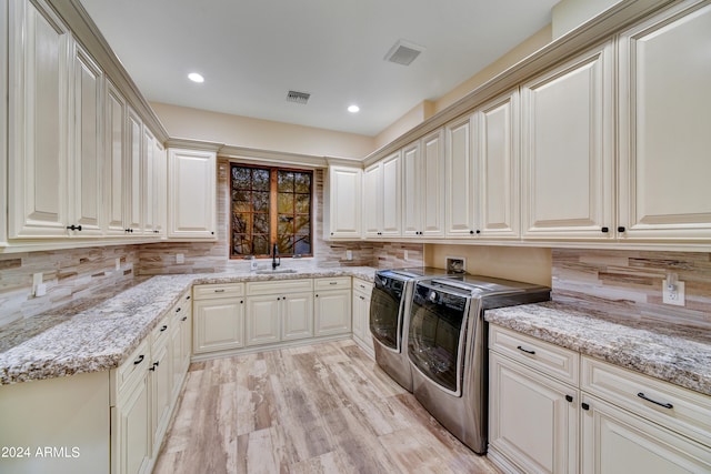 laundry room featuring light hardwood / wood-style flooring, washer and dryer, cabinets, and sink