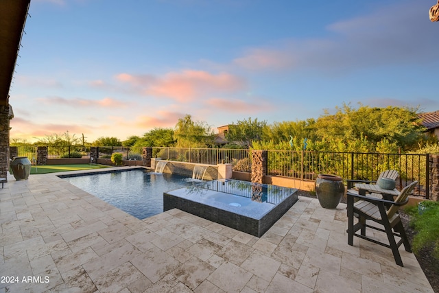 pool at dusk with a patio and pool water feature