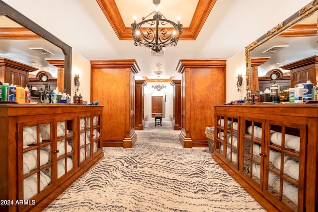 hallway with crown molding, light colored carpet, and an inviting chandelier