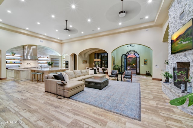 living room featuring light wood-type flooring, ceiling fan, and a stone fireplace