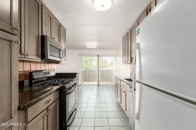 6767 N 7th St Unit 230, Phoenix, AZ 85014 - kitchen featuring freestanding refrigerator, black gas range, stainless steel microwave, light tile patterned flooring, and decorative backsplash
