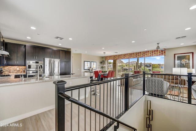 interior space with light stone counters, stainless steel appliances, tasteful backsplash, dark brown cabinetry, and sink