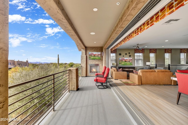 balcony featuring a large fireplace and ceiling fan