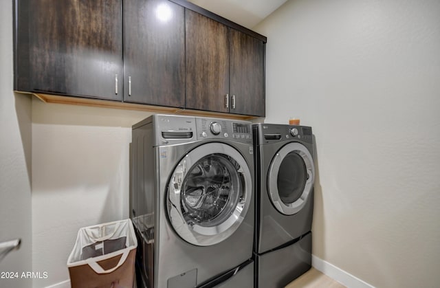 washroom with cabinets and washing machine and clothes dryer