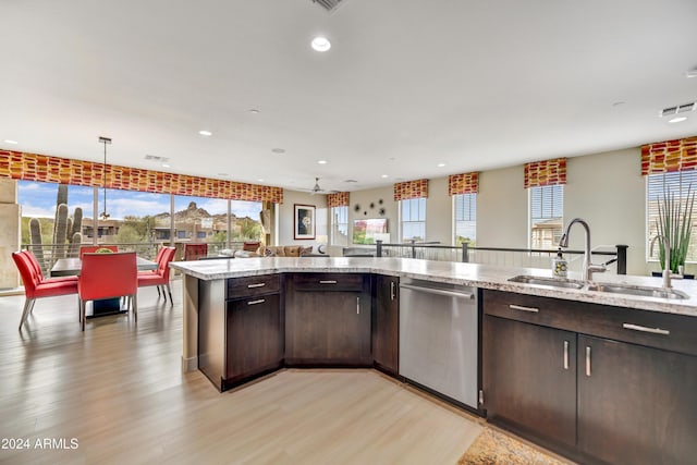 kitchen with light stone counters, stainless steel dishwasher, decorative light fixtures, dark brown cabinets, and sink