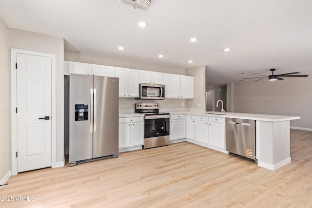kitchen with a sink, light wood-style flooring, stainless steel appliances, a peninsula, and visible vents
