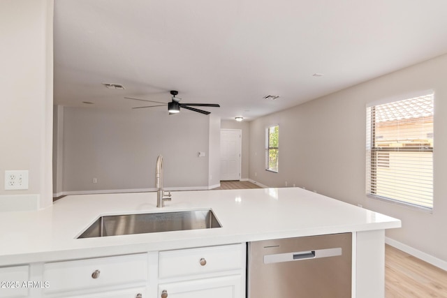 kitchen with stainless steel dishwasher, open floor plan, ceiling fan, white cabinetry, and a sink