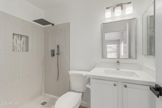 full bath featuring toilet, a tile shower, and vanity