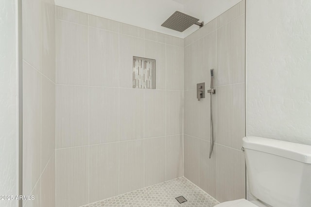 bathroom featuring toilet and a tile shower