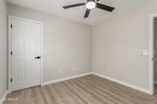 spare room with baseboards, a ceiling fan, and light wood-style flooring