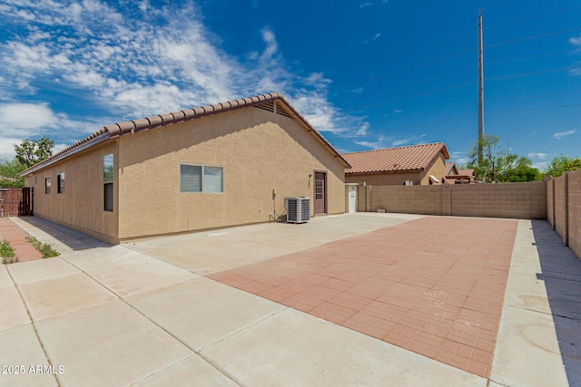back of house featuring a tile roof, cooling unit, a fenced backyard, a patio, and stucco siding
