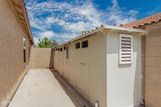 view of home's exterior with stucco siding, an outbuilding, a shed, and fence