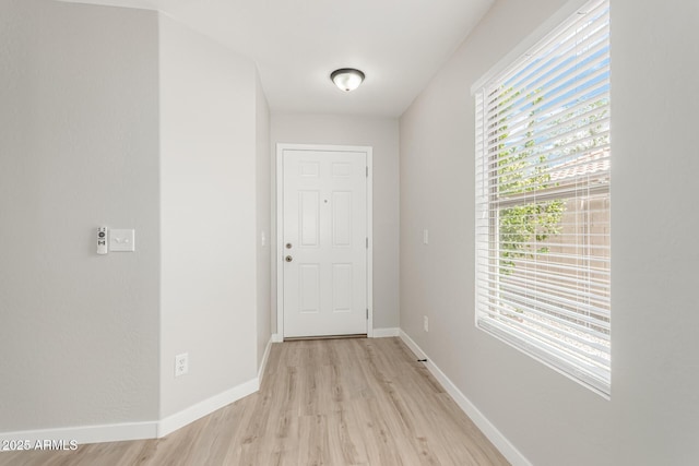 doorway featuring baseboards and light wood finished floors