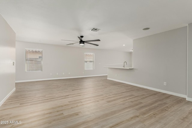 unfurnished living room featuring light wood-style floors, baseboards, a ceiling fan, and visible vents