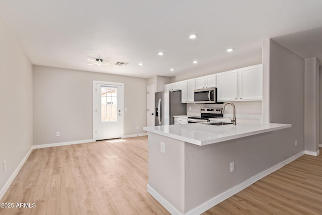 kitchen featuring a sink, appliances with stainless steel finishes, light wood finished floors, and visible vents