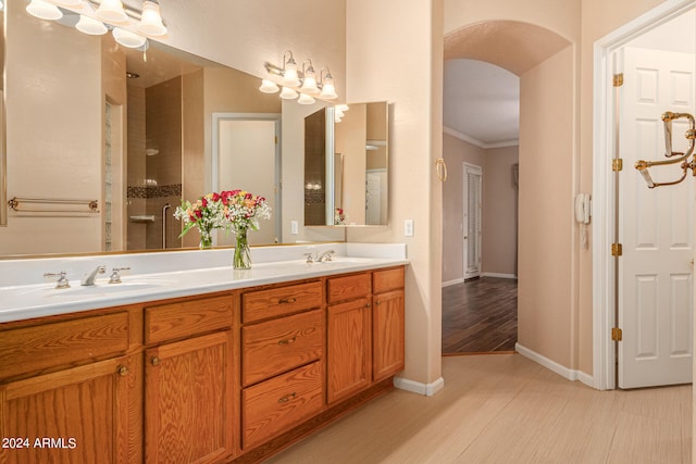 bathroom with a shower, crown molding, wood-type flooring, and vanity