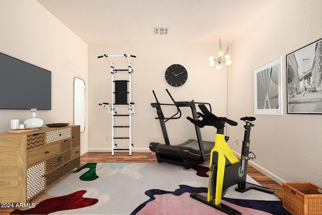 exercise room featuring wood-type flooring and a chandelier