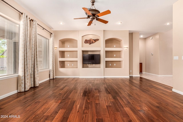 unfurnished living room with ceiling fan, built in features, and dark hardwood / wood-style flooring