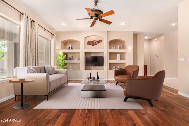 living room featuring built in shelves, dark hardwood / wood-style floors, and ceiling fan